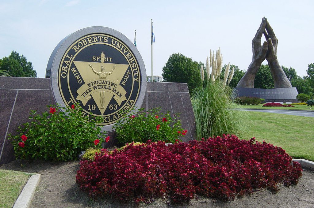 Photograph of the Praying Hands bronze sculpture and the Avenue of Flags at the main entrance to Oral Roberts University
